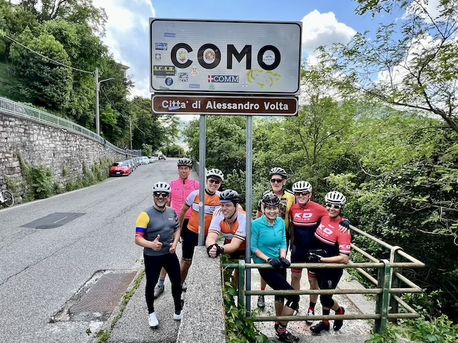 cyclists in front of como sign